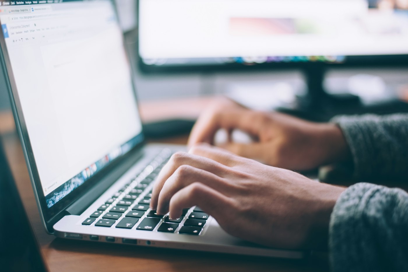 Hands typing on a laptop while working through a document